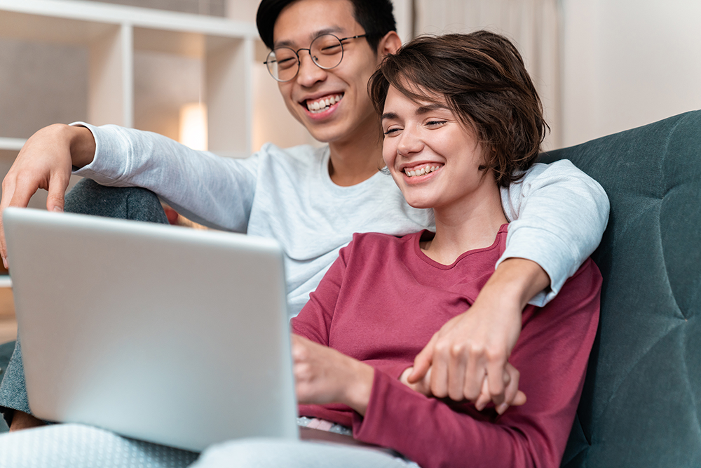 Couple smiling looking at computer.