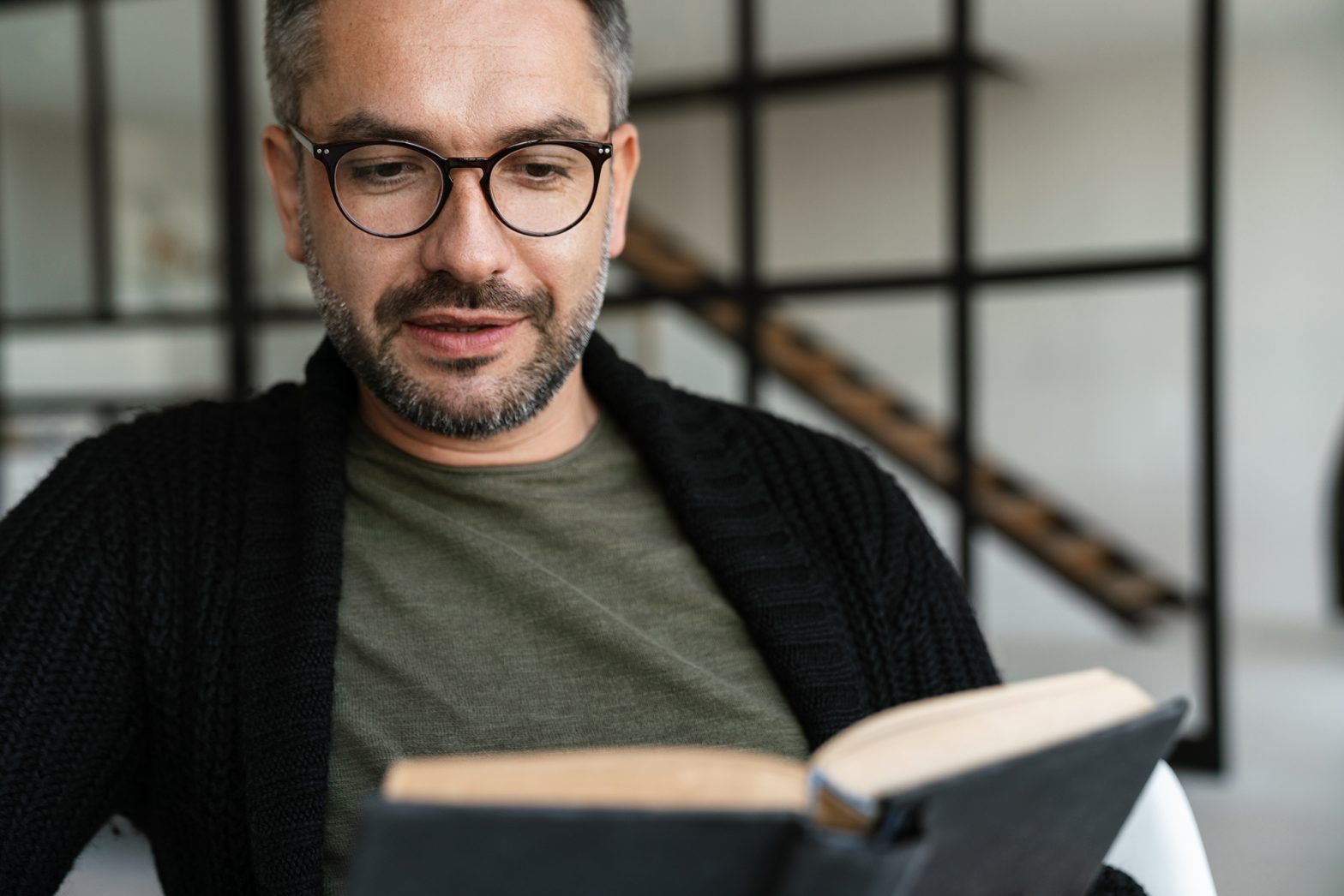 Confident middle-aged man reading a men's health book at home, focusing on personal wellbeing