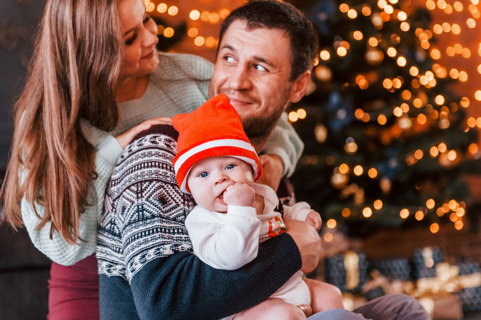 Father and mother spending time with their child in a Christmas-decorated room, enjoying family moments together