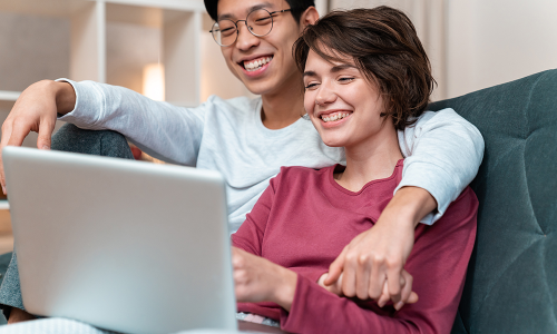 Couple smiling looking at computer.